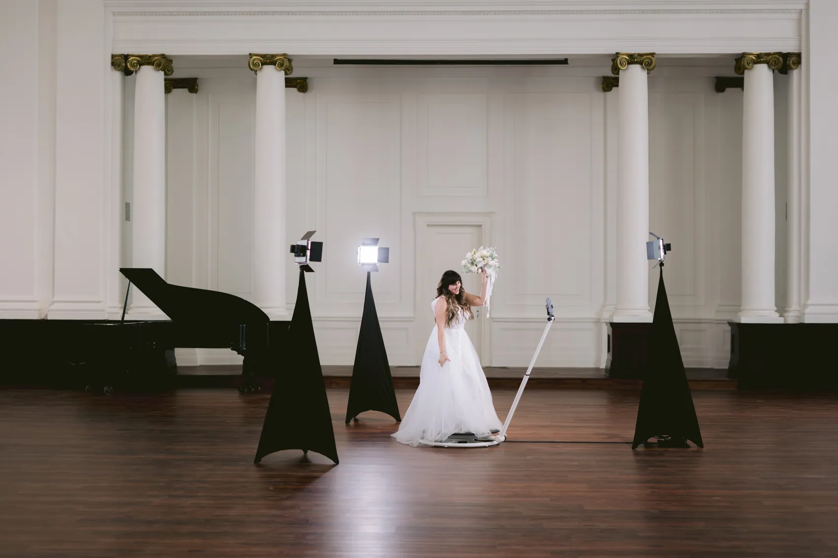 A bride stepping onto the 360 platform in a columned ballroom
