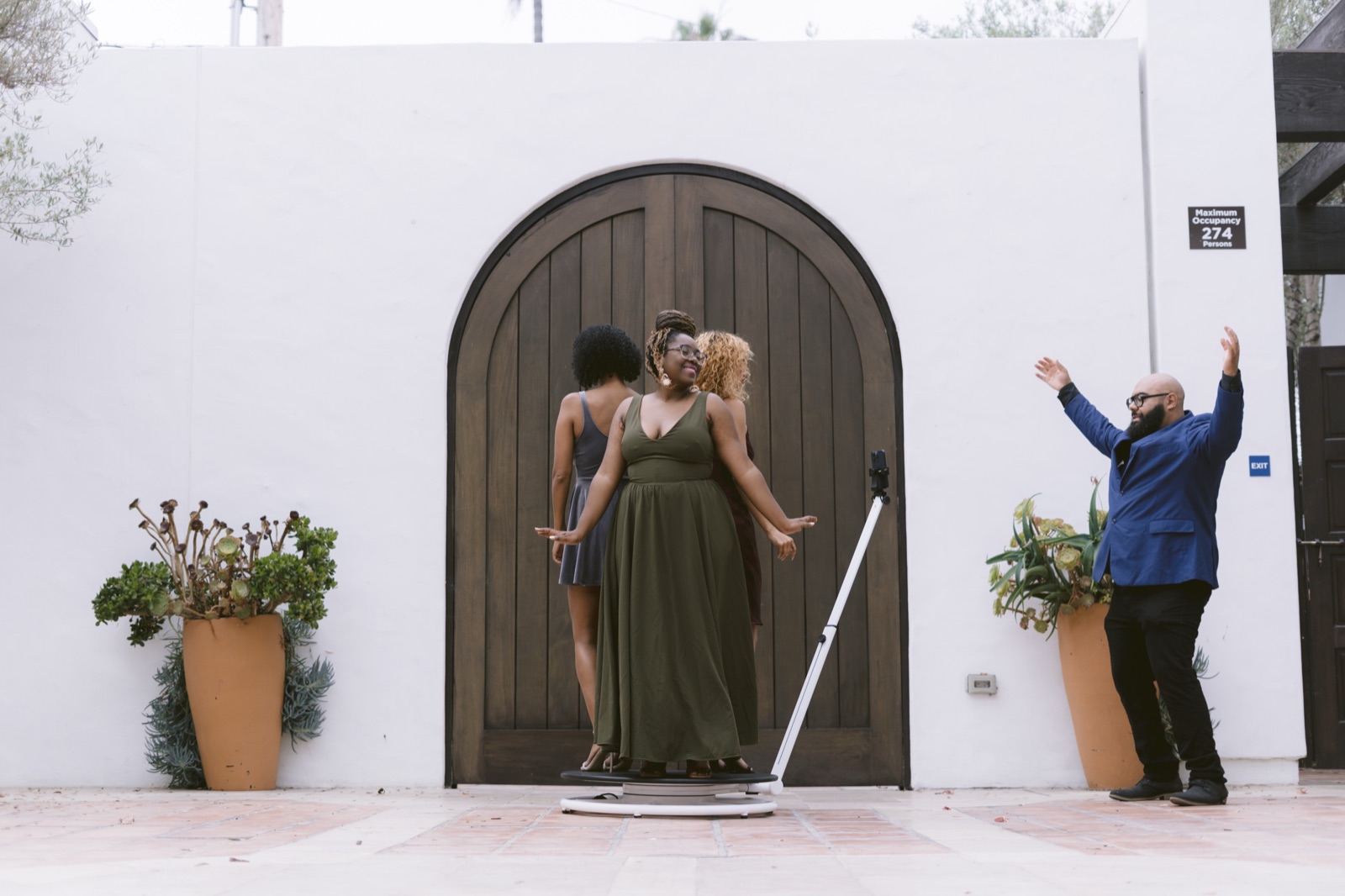 Guests posing on the spinning platform outside a wooden arched doorway while another guest throws his arms up beside them