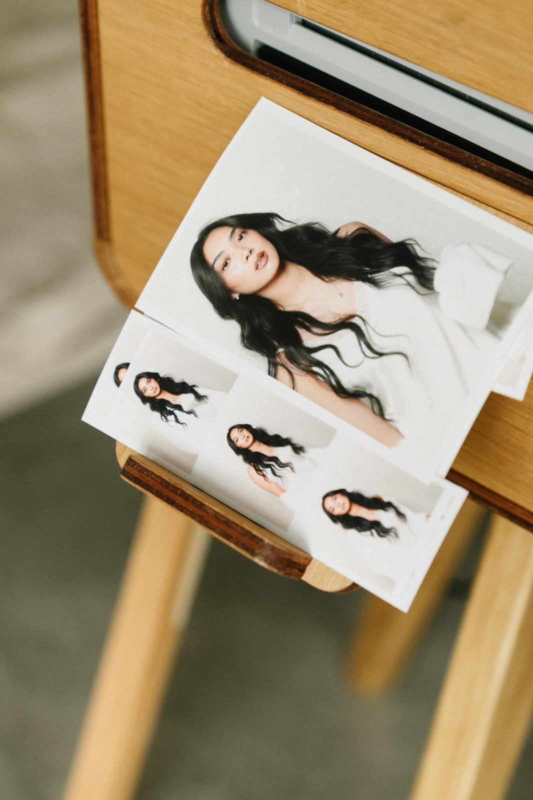 A finished print resting on the wooden booth stand, the same portrait repeated down a strip beside it