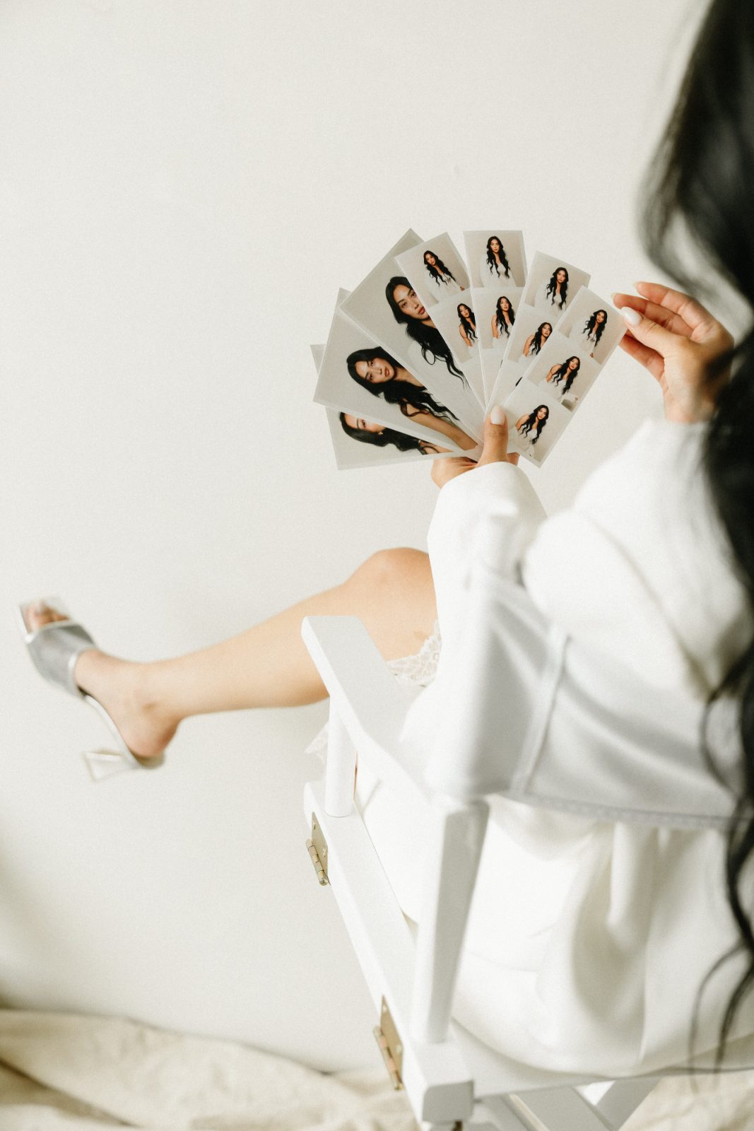 A guest sitting with one heel kicked out, fanning a handful of freshly printed photo strips